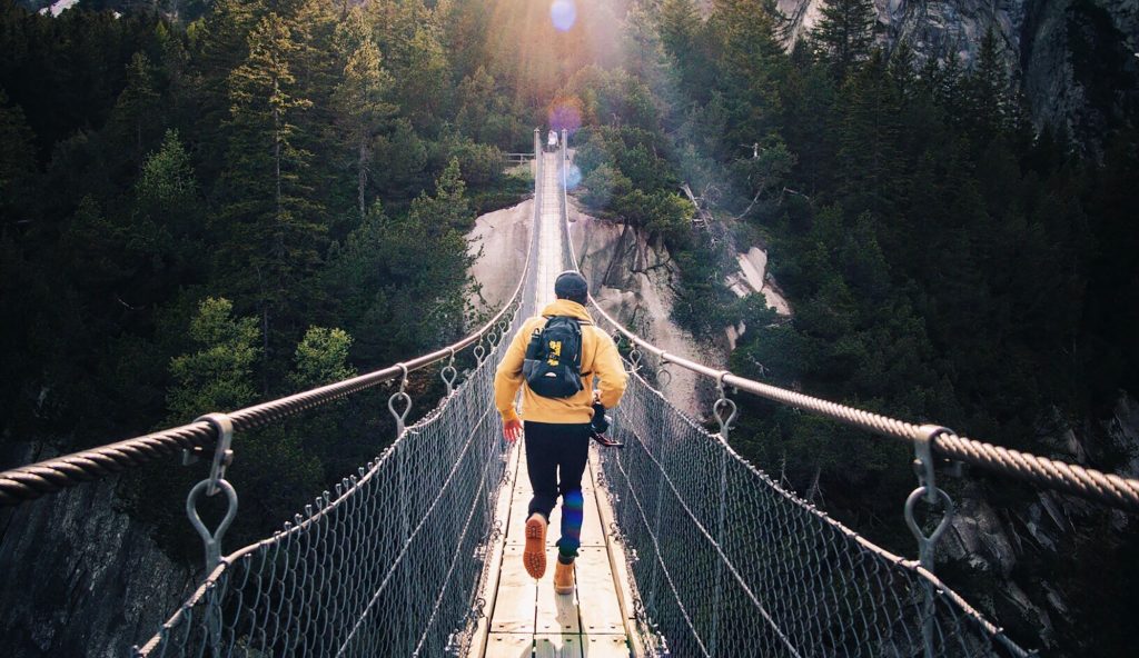 A person on the rope bridge is moving towards the other side of the mountain.
